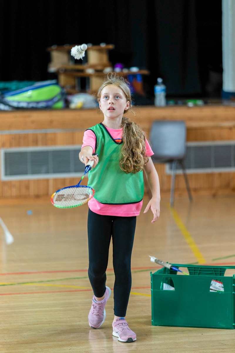 girl in pink tank top and black pants holding white and blue tennis racket